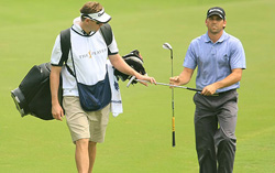 A golfer walking with a caddy